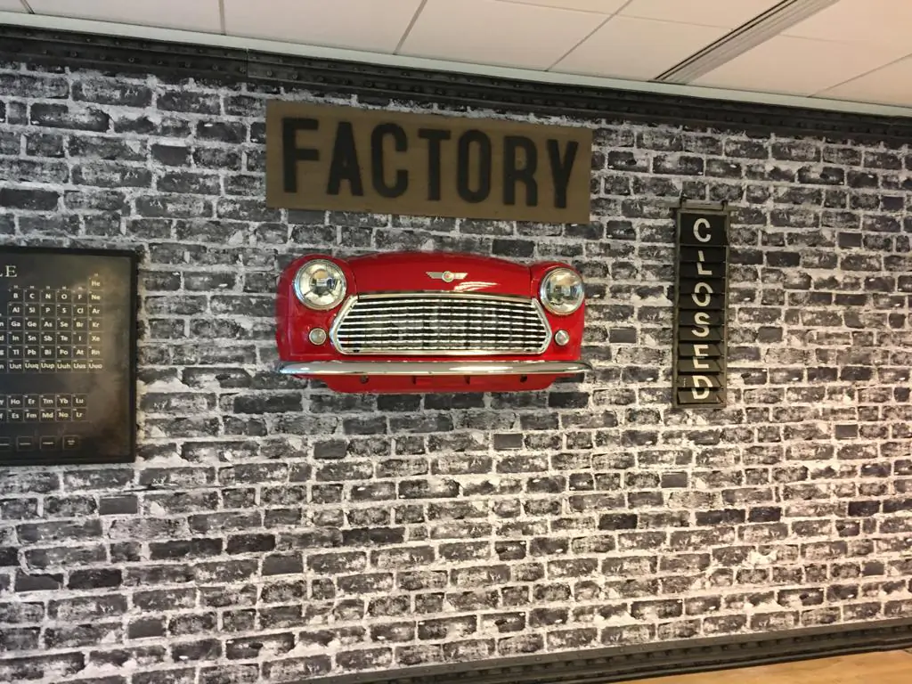 Mur « Factory » AXA Banque : papier peint brique et calandre de Mini rouge