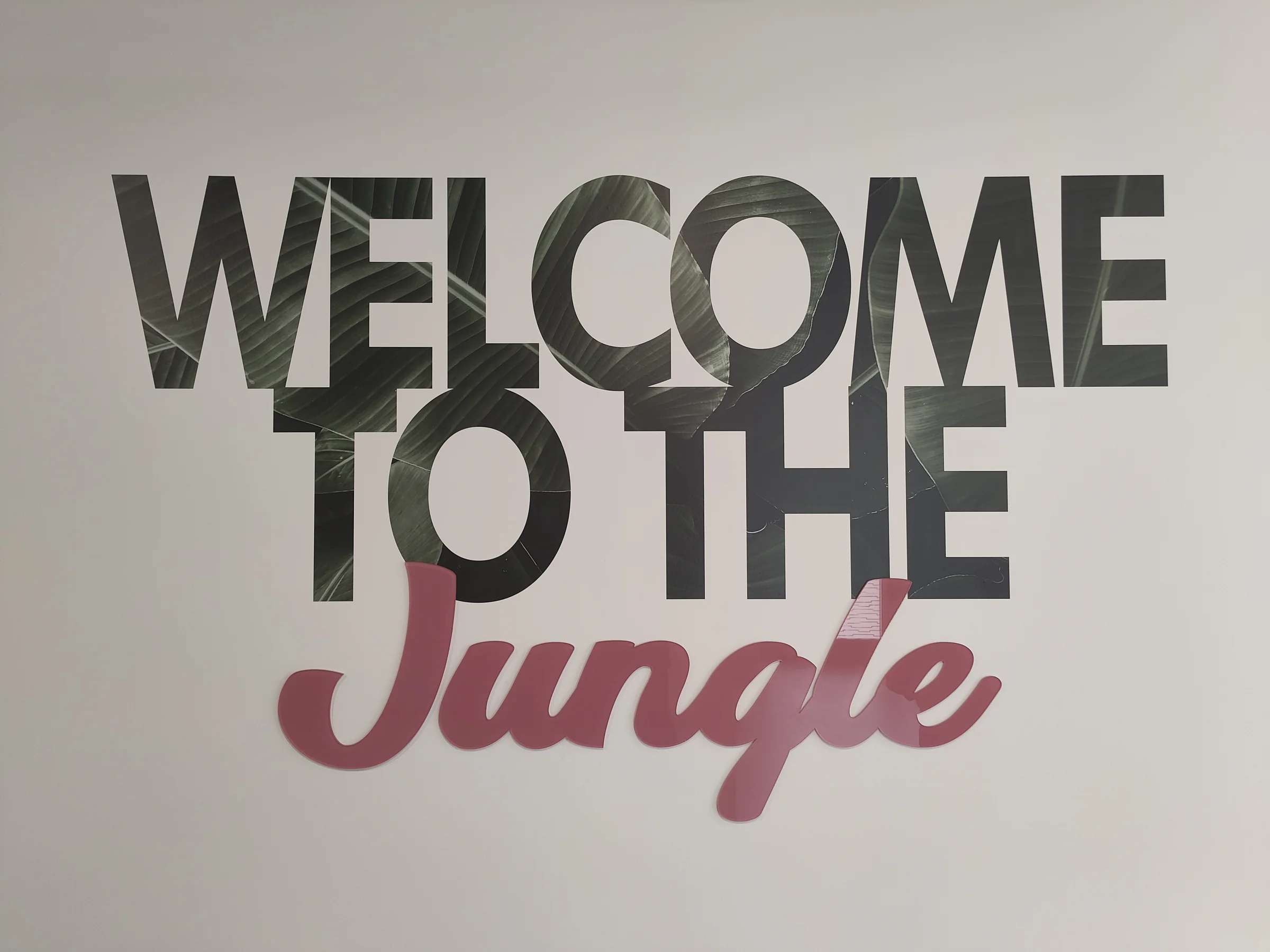 Lettrage « Welcome to the Jungle » en relief noir et rose sur mur blanc, bureaux AXA