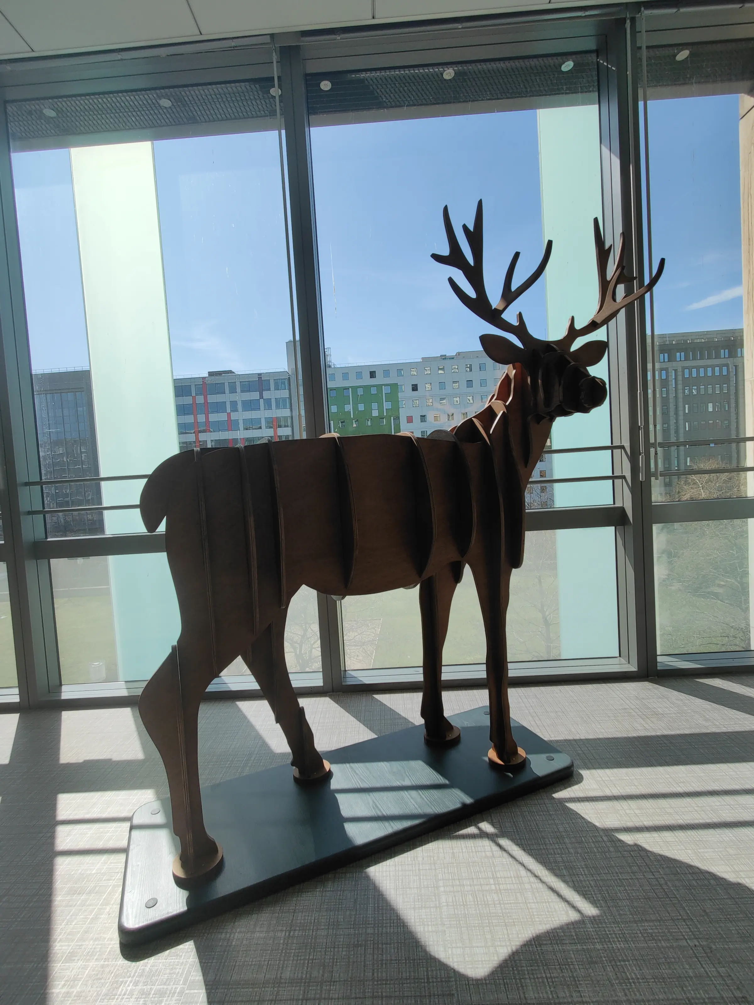 Cerf en bois découpé près d'une baie vitrée, bureaux de style scandinave