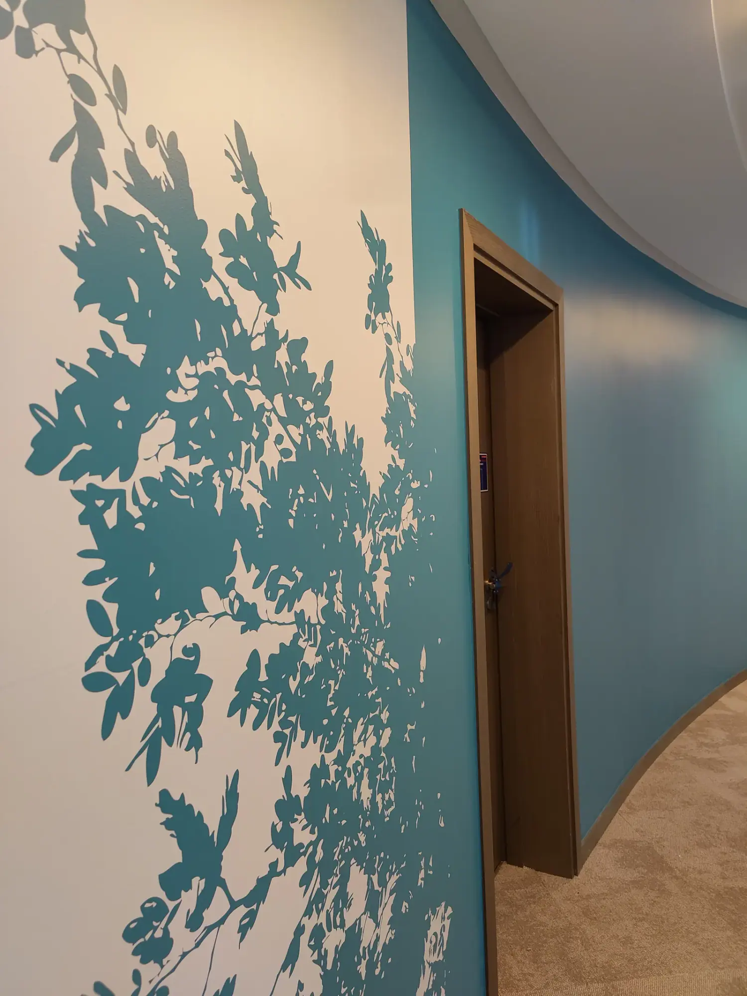 Couloir courbe AXA Opéra : feuillages bleu canard peints en adhésif sur mur blanc