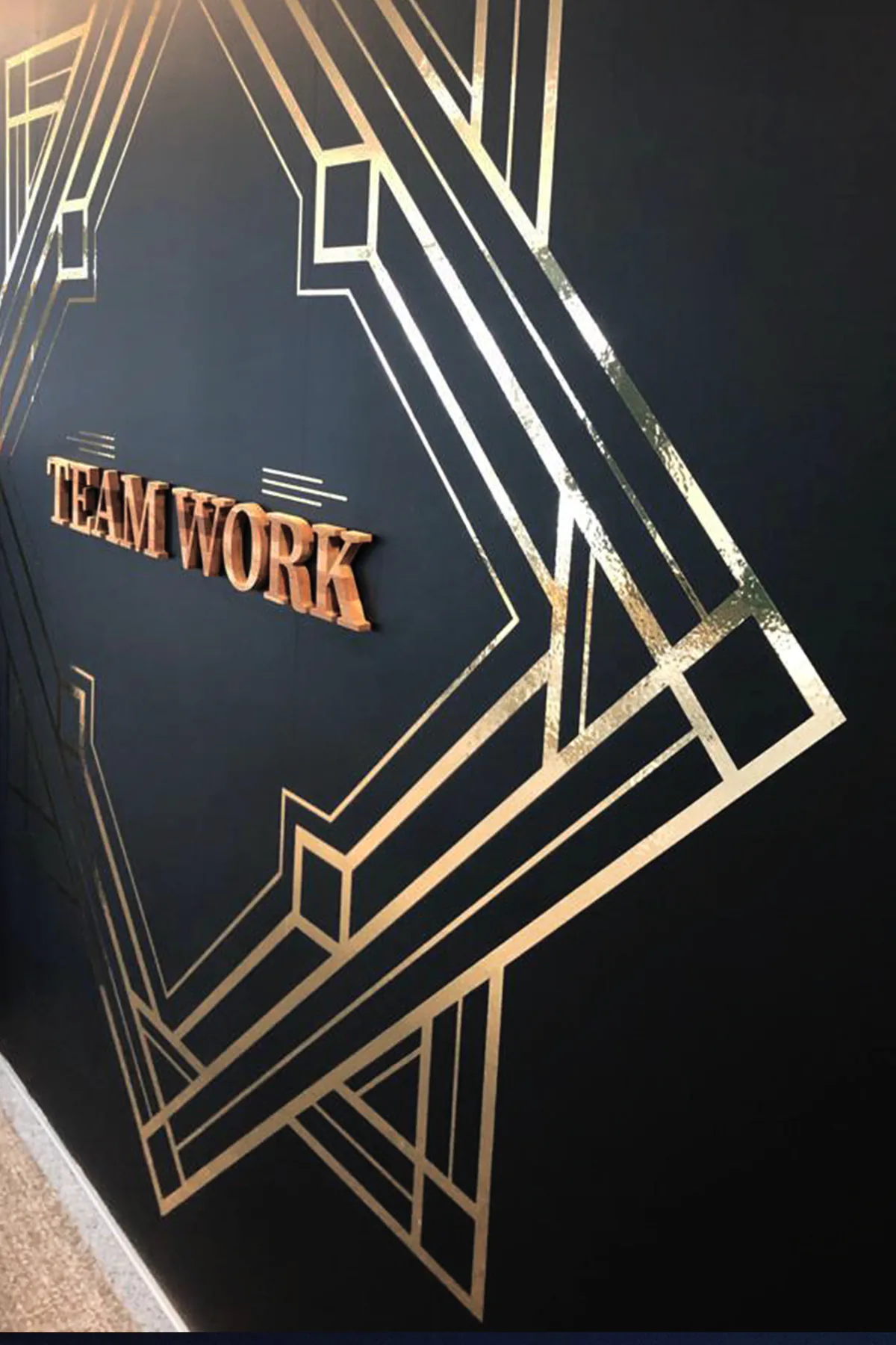 Filets dorés effet miroir et lettrage Team Work cuivré sur mur noir, décoration art déco de bureaux