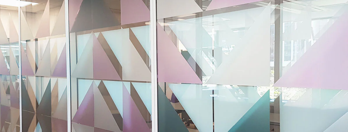 Vitrophanie scandinave en triangles blancs, rose pâle et bleu canard sur les cloisons vitrées de bureaux d'assurance