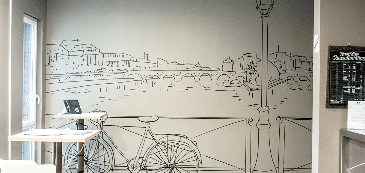 Mur de la cafétéria DGGN dessiné au trait noir : quais de Seine, pont, réverbère et vélo en adhésif découpé