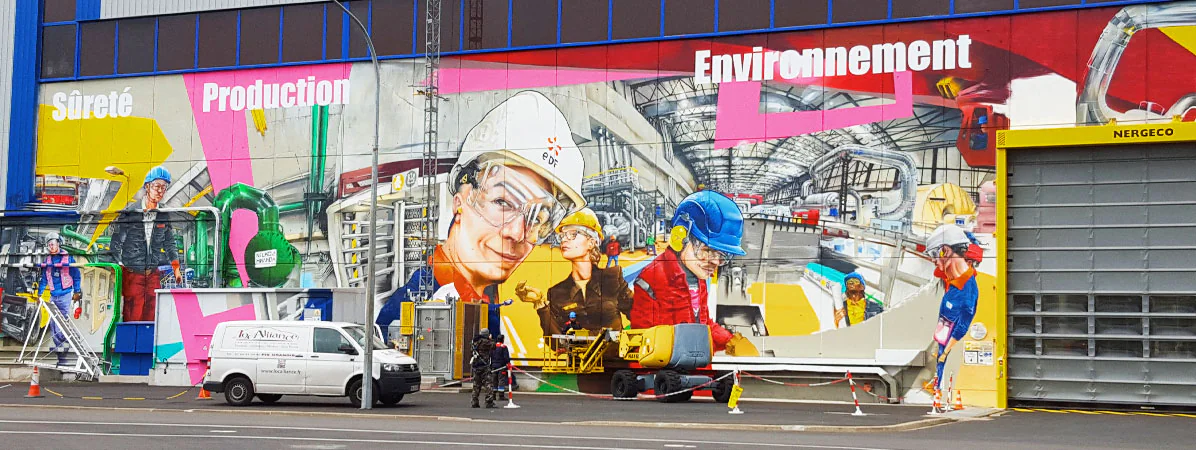 Fresque graffiti géante sur un site EDF : techniciens casqués et mots Sûreté, Production, Environnement en lettrage