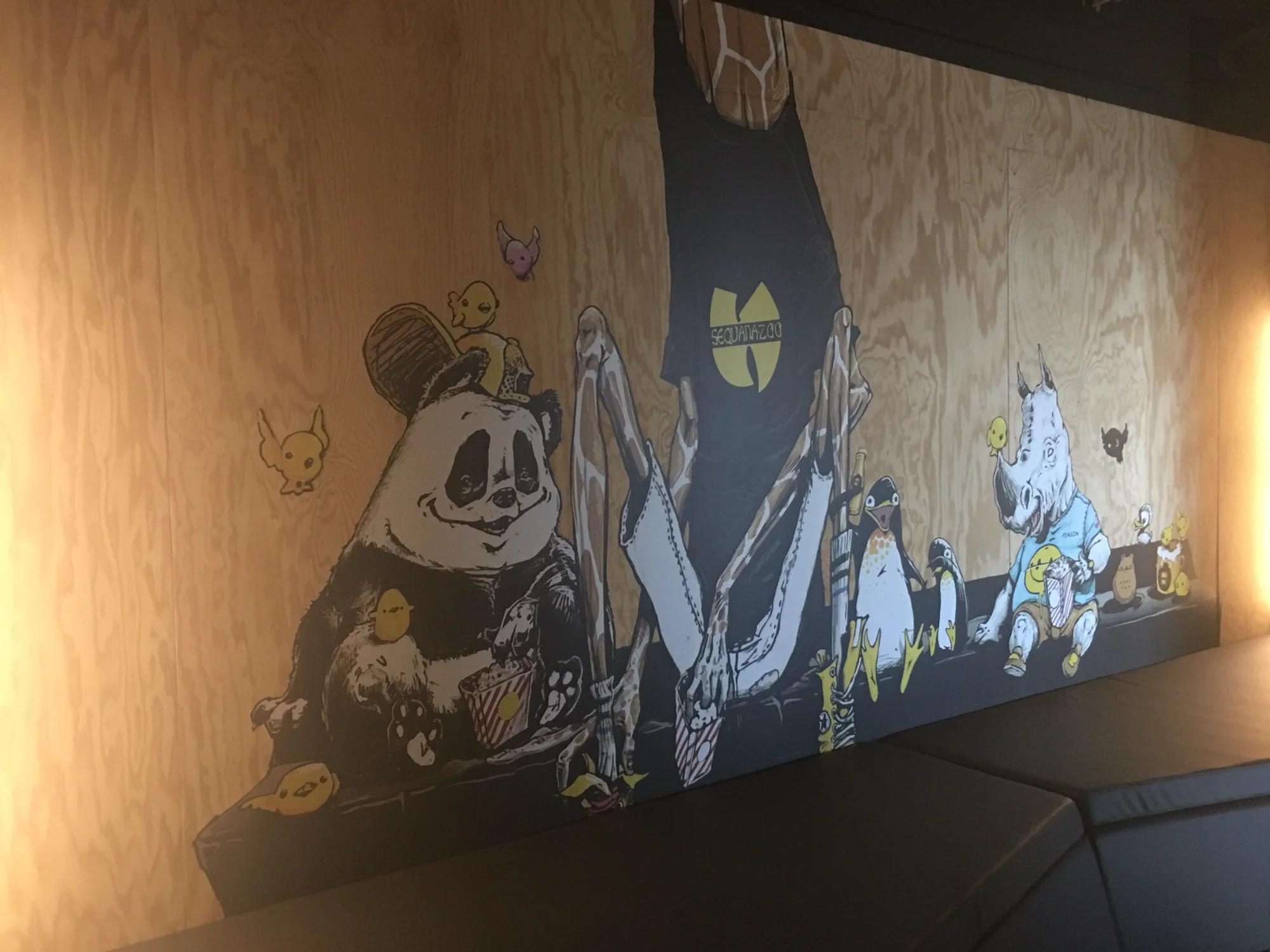 Fresque street art sur bois brut à l'hôtel Jo&Joe : panda, rhinocéros et petits personnages en adhésif mural