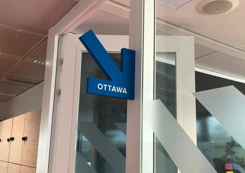 Flèche signalétique bleue Ottawa en relief sur une cloison vitrée des salles de réunion SNCF, par Paristic