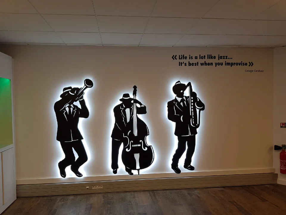 Silhouettes rétroéclairées de trois musiciens de jazz peintes sur un mur de bureau