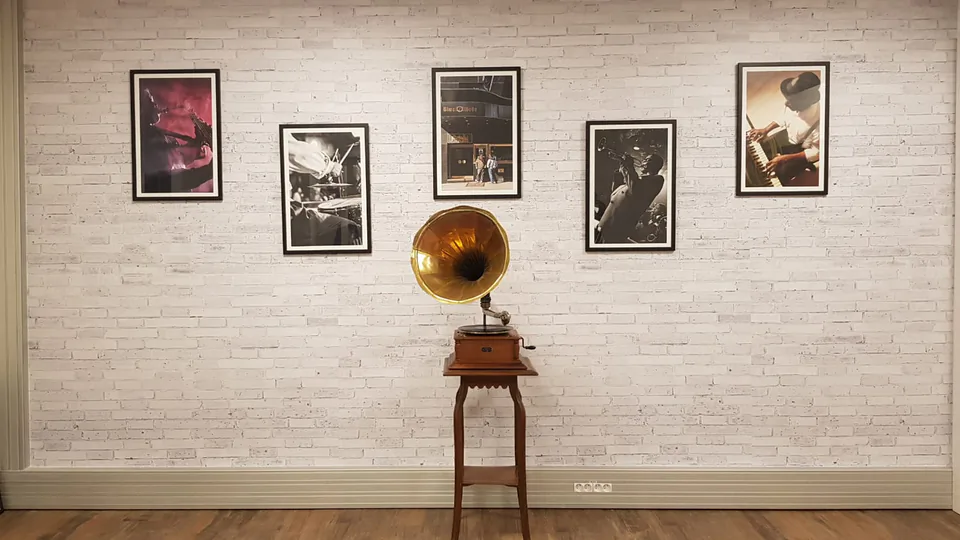 Mur en briques blanches habillé de photos de jazz encadrées autour d'un gramophone ancien