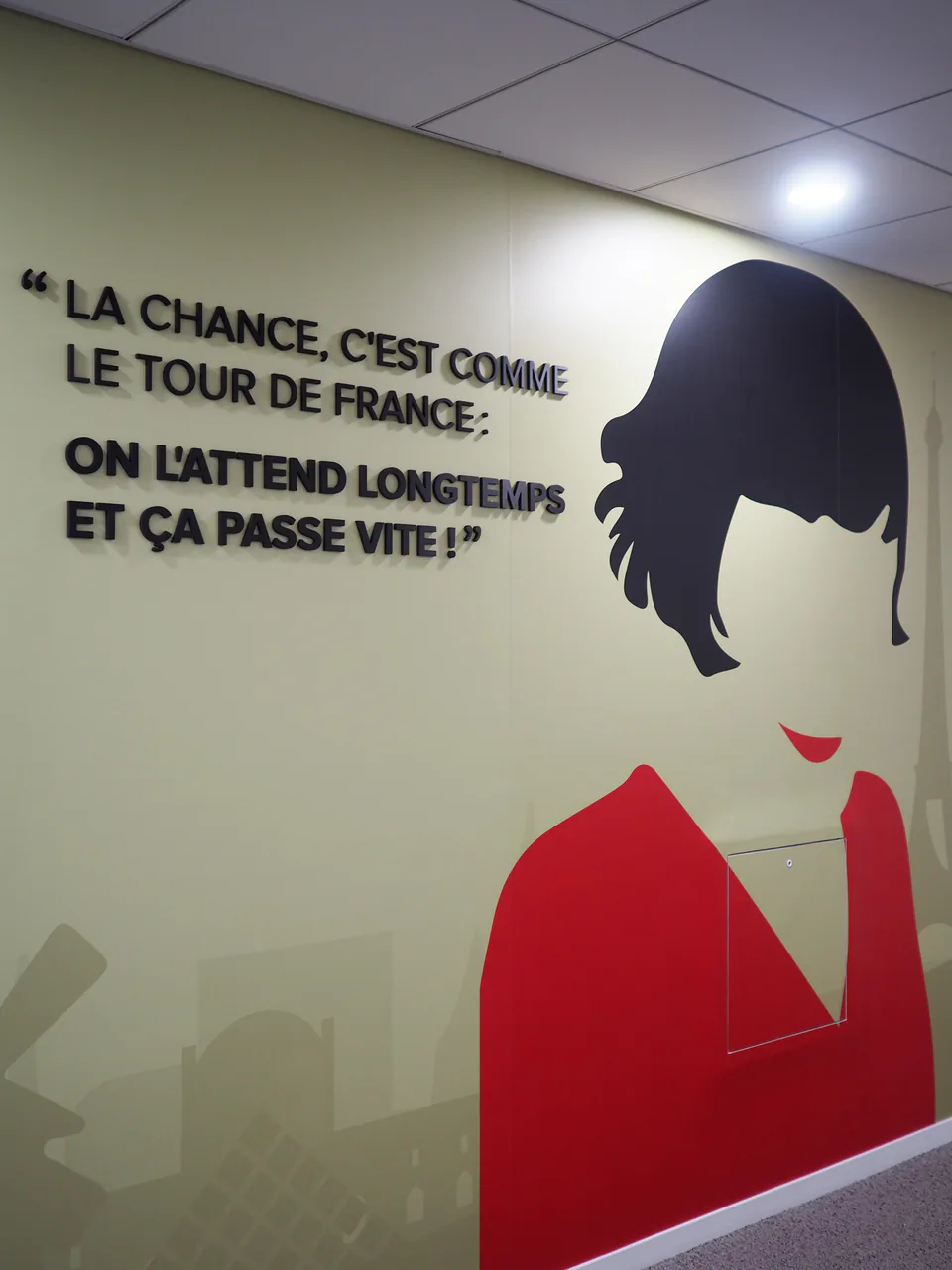 Mur de bureau avec une citation en lettres 3D noires et la silhouette peinte d'une femme en rouge