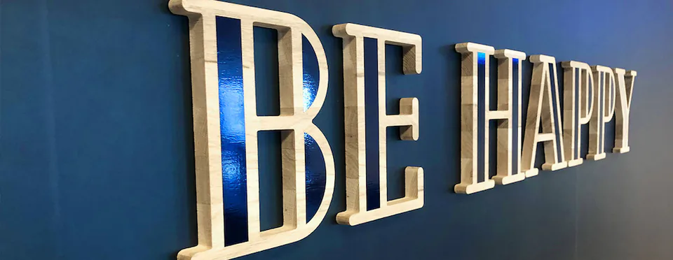 Gros plan sur les lettres en bois du message « Be Happy » en relief