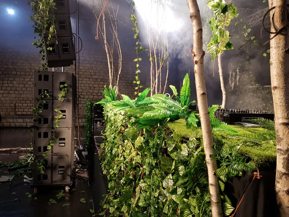 Décor végétal stabilisé façon forêt habillant des enceintes et un pupitre DJ sur une scène
