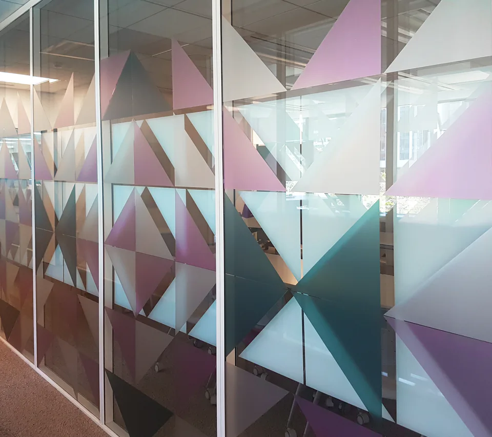 Couloir de bureau avec le même motif de triangles en vitrophanie sur plusieurs parois vitrées