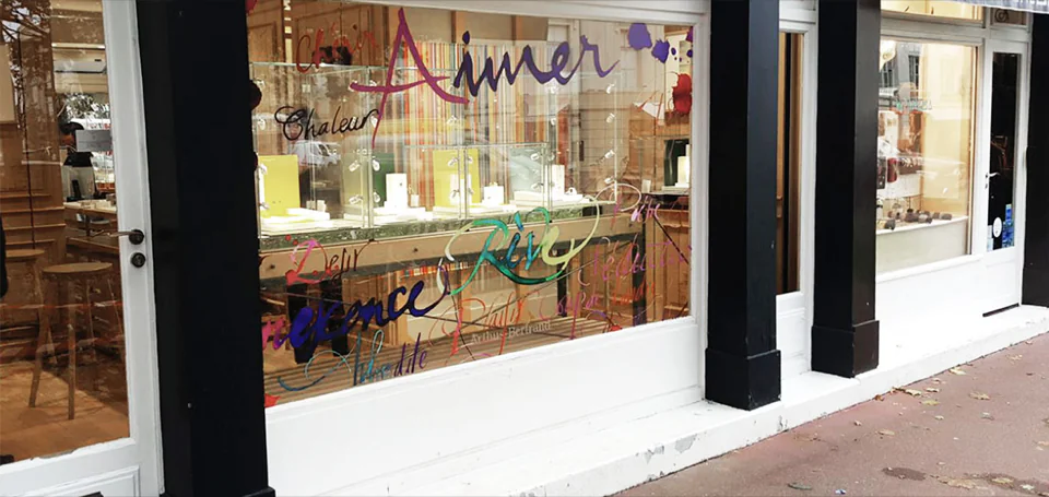 Vitrine Arthus-Bertrand avec des mots calligraphiés colorés sur le verre