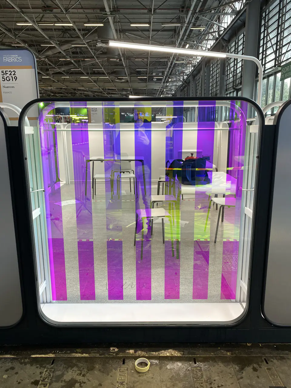 Paroi vitrée à bandes verticales violettes et roses sur un stand