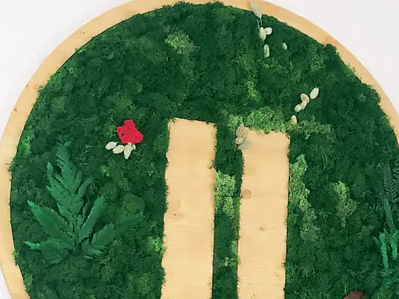 Gros plan sur la mousse stabilisée et les lettres en bois clair d'un logo végétal rond